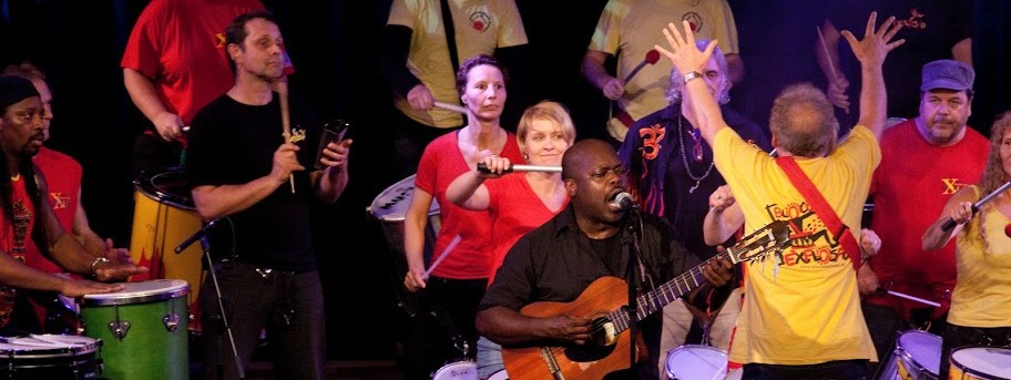 singer-guitarist performing with a percussion group playing behind him