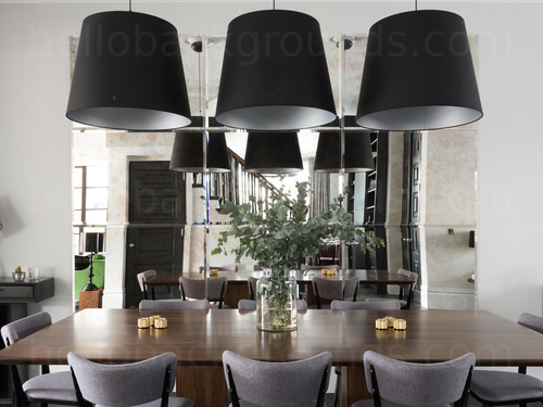 Modern dining room decorated in dark and light pastel colours featuring a dining table with 3 large hanging overhead lights Skype background
