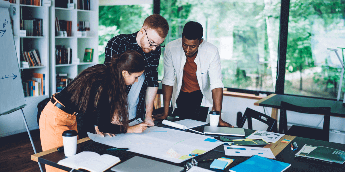 Data science in the finance industry: Top use cases Three data scientists leaning over a desk, looking at documents
