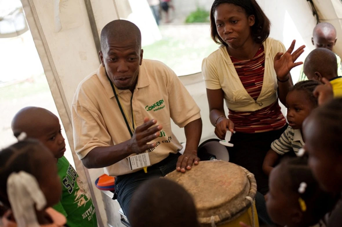 Children being entertained by a man playing a drum.