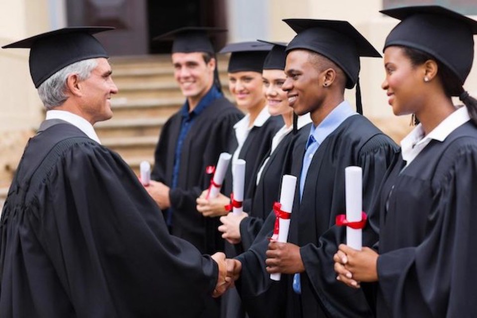 The university Dean shaking hands with students dressed for a graduation ceremony
