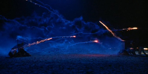 A screenshot from the movie 'Sonatine' of a fireworks fight on the beach at night.
