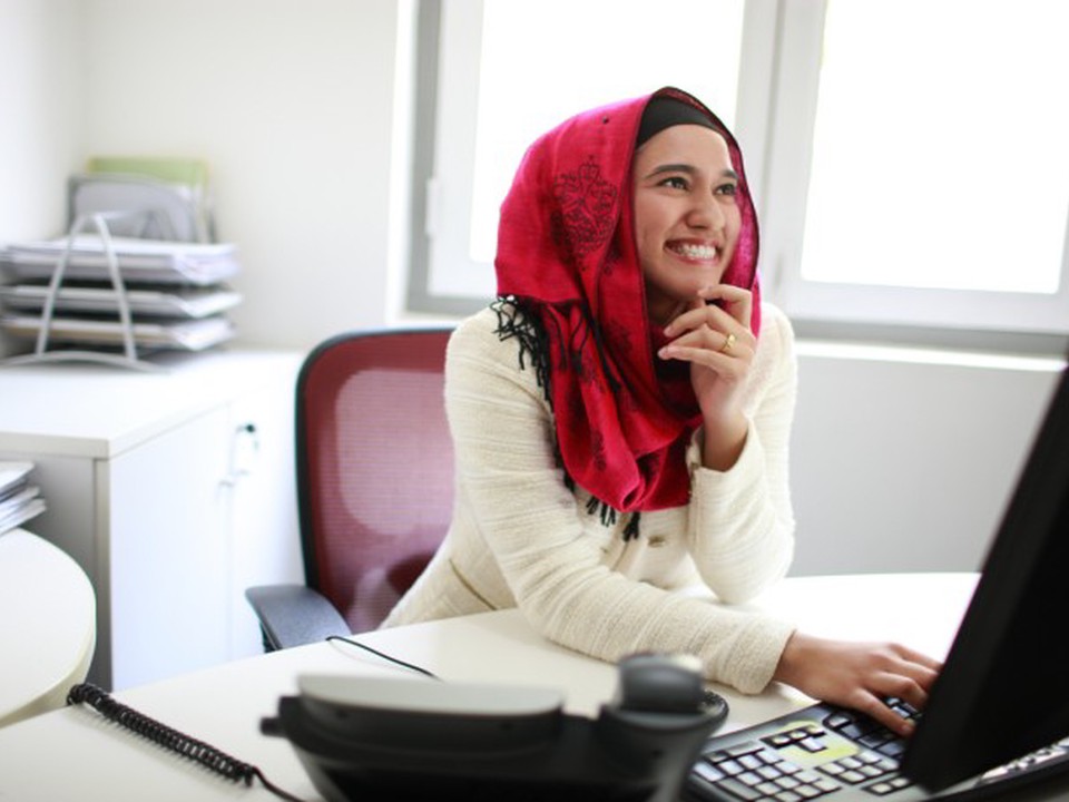 An inspired social worker smiles while reading an inspirational quote on the computer.