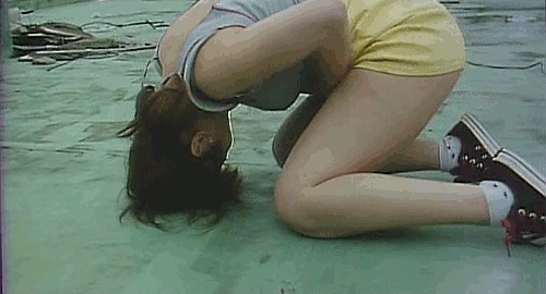 An animated gif of a scene from the movie 'The Glamorous Life of Sachiko Hanai' of a woman in yellow short on a rooftop feverishly touching herself.