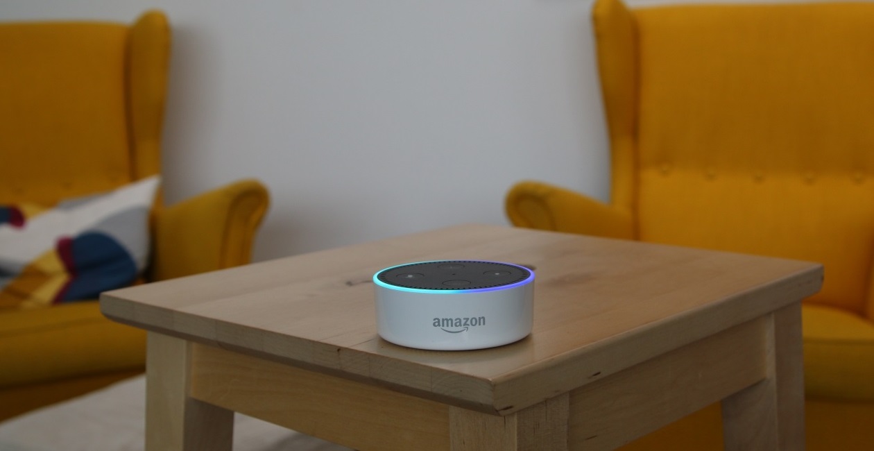 Amazon Alexa sitting on top of a wooden stool Amazon Alexa sitting on top of a wooden stool in a living room