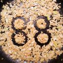 Chopped onion cooking in a frying pan. The onion is pushed away in four rings, touching in pairs, forming the number eighty eight.
