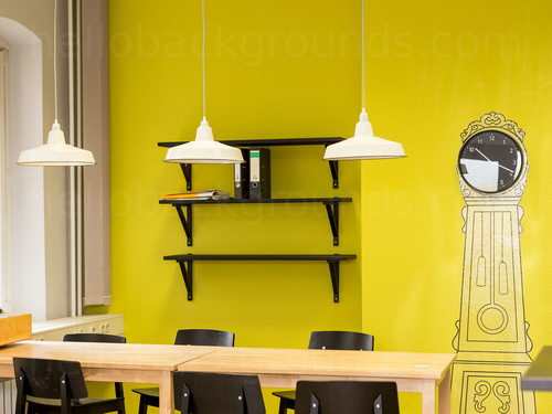 Quirky bright yellow decorated workspace with wooden table and black chairs next to wall painted grand mirror    Zoom background