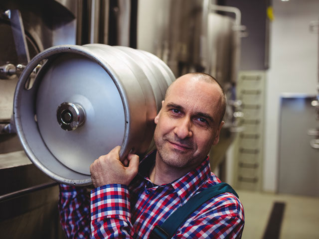 A brewery production manager carrying a keg of beer for distribution