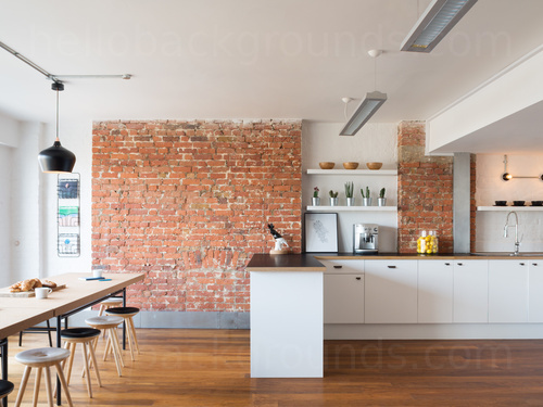Modern shared workspace featuring exposed brick wall with wooden stools table and flooring next to kitchen storage  Zoom background
