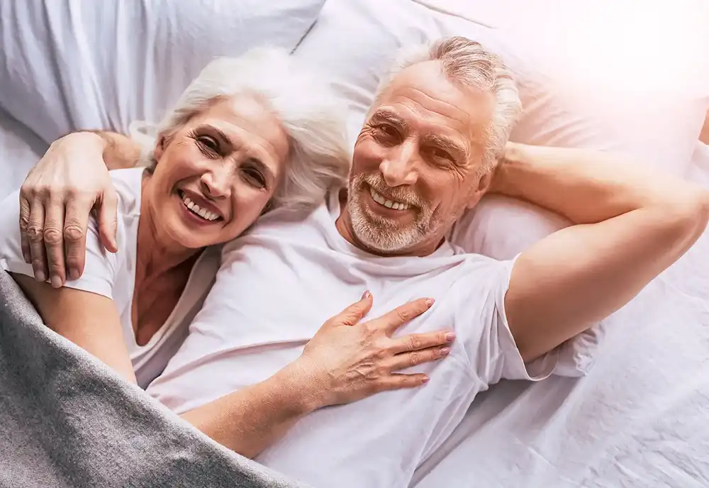 Healthy, happy, fit senior man and woman relaxing in bed