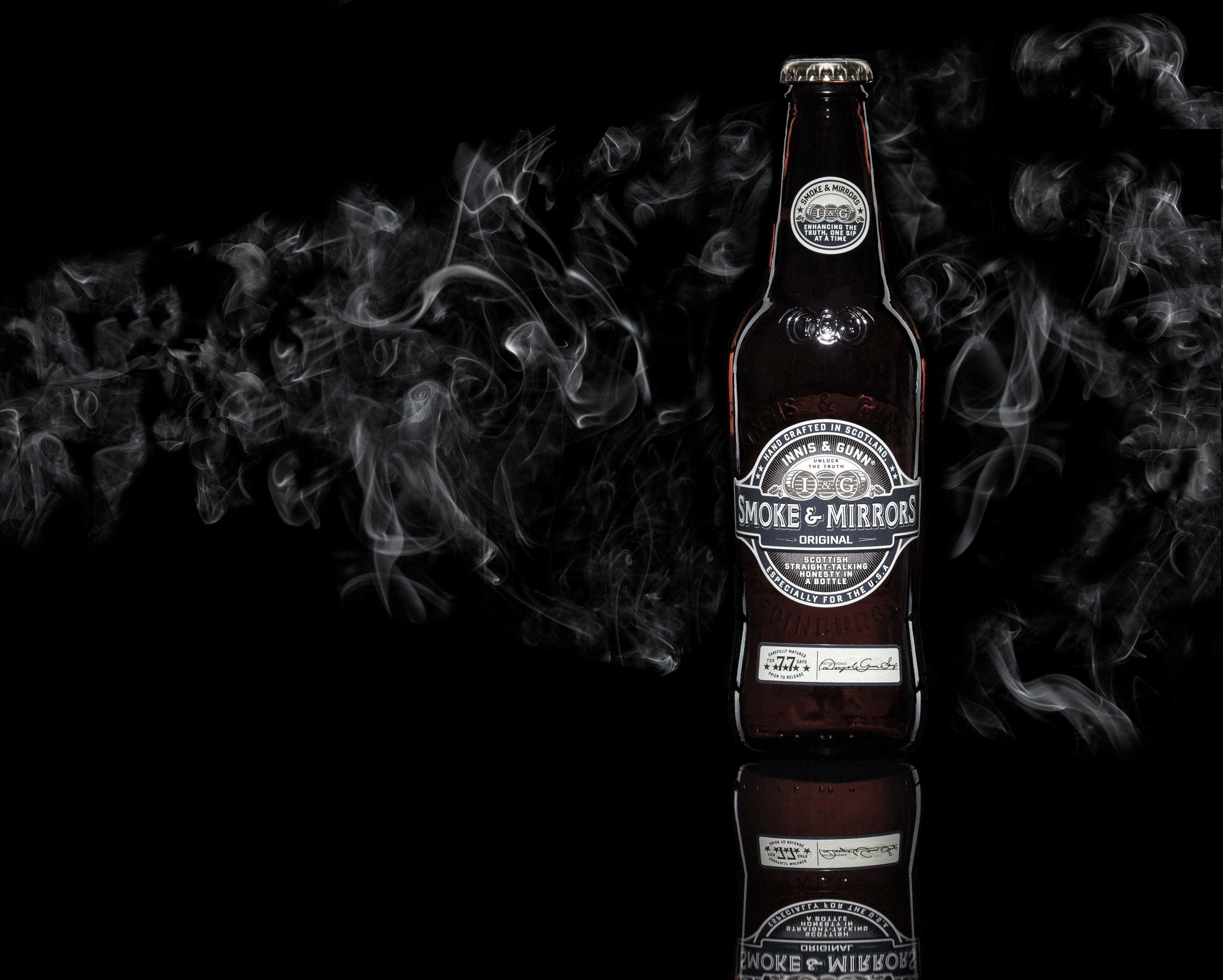 Innis Gunn bottle of beer on a black background with smoke behind.