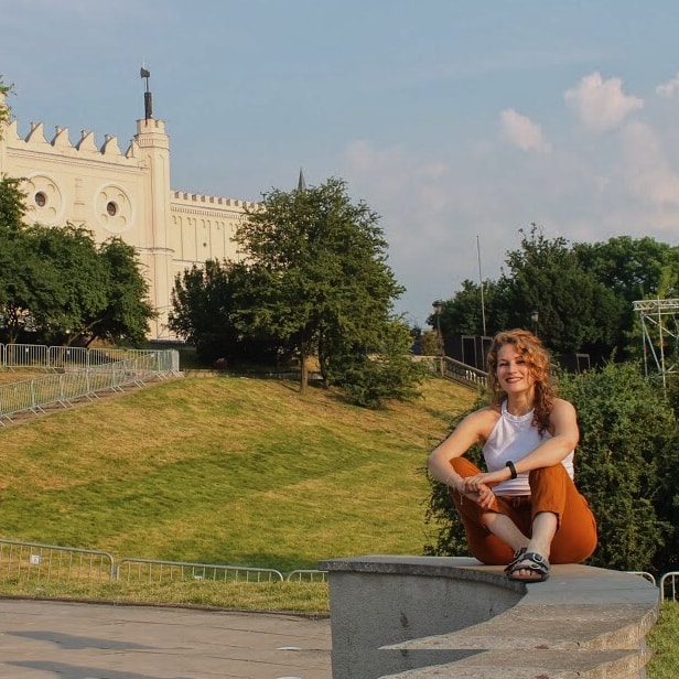 Leticia López Martínez sentada al aire libre con la ciudad de Lublin detrás