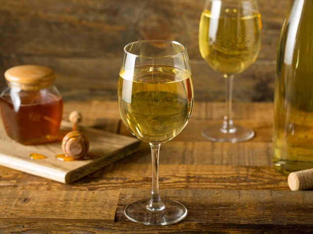 A glass of Honey Wine Mead along with a jar of honey and bottle of Mead