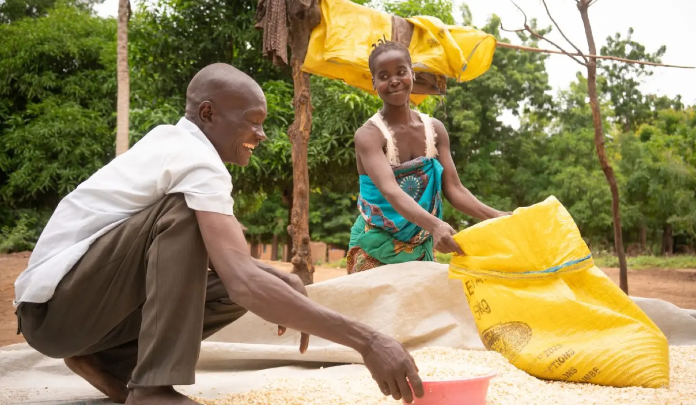 Malawian Forty Sakha helps his wife Chrissy with household chores like drying maize.