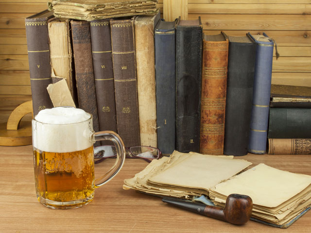 A full mug of beer amid old homebrewing books on a desk