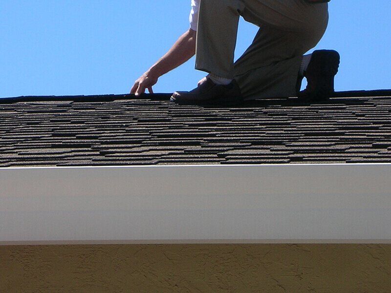 Man inspecting roof of house