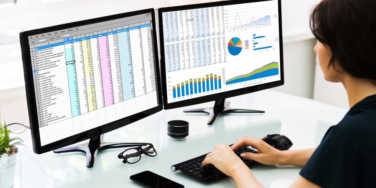 Conditional formatting in Excel A data analyst in side profile, looking at spreadsheets on two computer screens