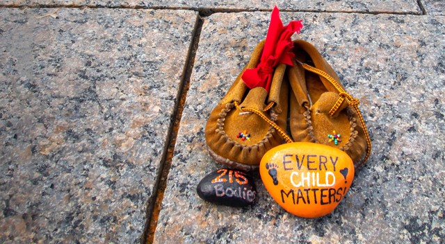 Children&#039;s shoes and a painted orange rock that reads &quot;Every Child Matters&quot; site at a memorial at Canada&#039;s Parliament Hill for Indigenous children who were sent to Residential Schools